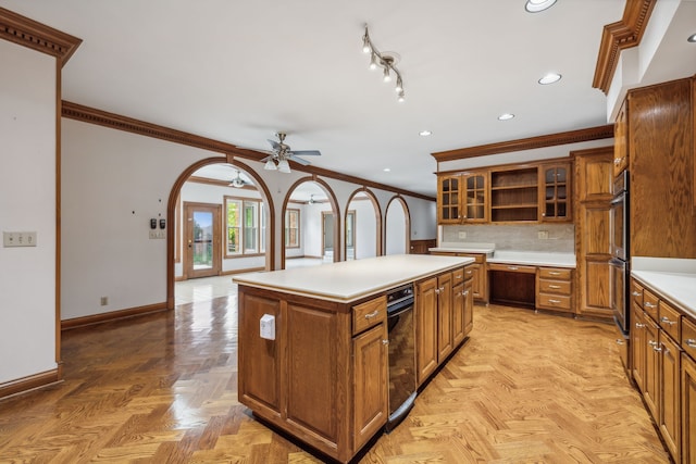 kitchen with ceiling fan, a center island, tasteful backsplash, light parquet flooring, and ornamental molding