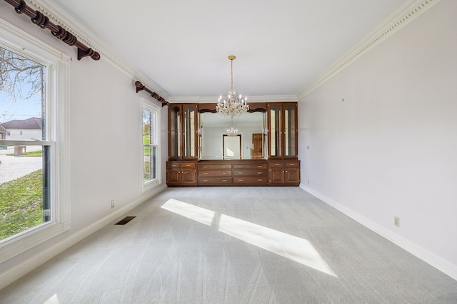 unfurnished dining area featuring light carpet, an inviting chandelier, plenty of natural light, and ornamental molding