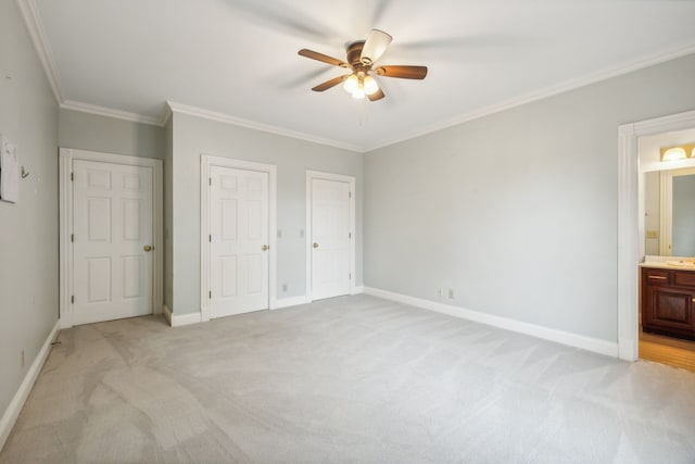 unfurnished bedroom with connected bathroom, ceiling fan, multiple closets, crown molding, and light colored carpet