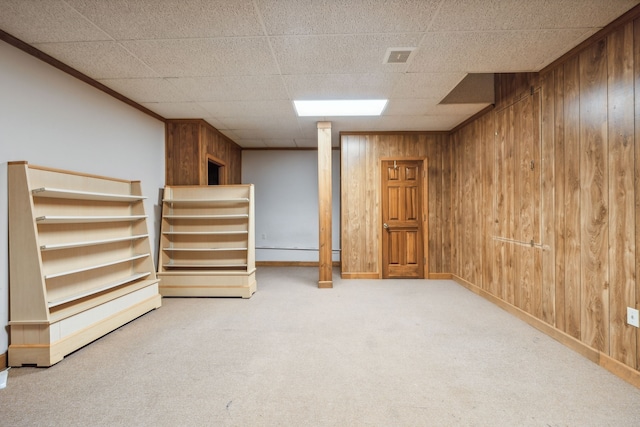 basement with a paneled ceiling, wooden walls, and carpet