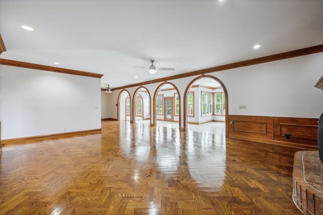 unfurnished living room with dark parquet floors, ceiling fan, and crown molding