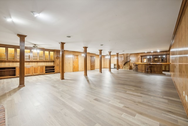 basement with wood walls, light hardwood / wood-style flooring, ceiling fan, and ornamental molding