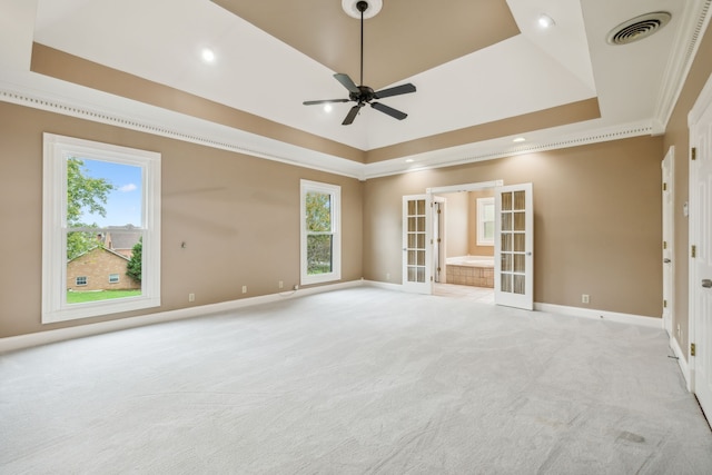 unfurnished room with light carpet, french doors, ornamental molding, a tray ceiling, and ceiling fan