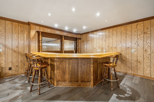 bar with wooden walls, dark wood-type flooring, and ornamental molding