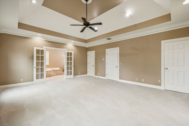 empty room with a raised ceiling, light colored carpet, and french doors