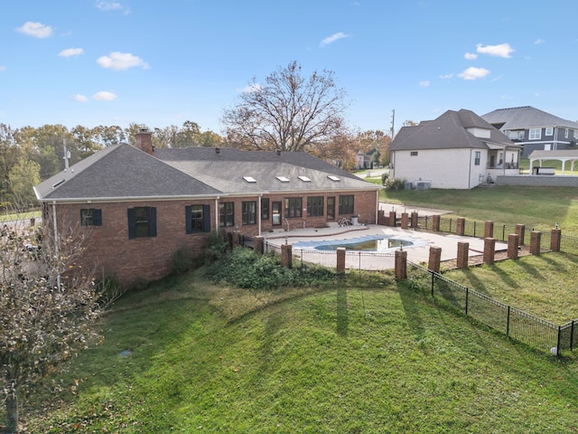 rear view of property featuring a lawn, a fenced in pool, and a patio