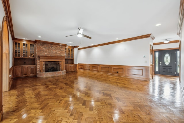 unfurnished living room featuring crown molding, parquet floors, and a brick fireplace