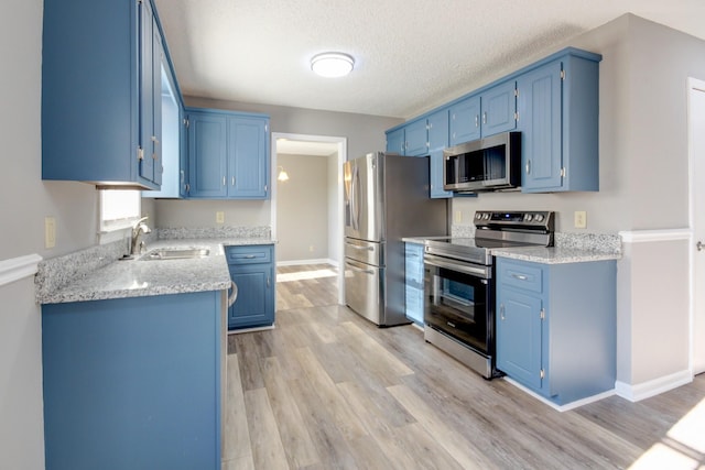 kitchen featuring blue cabinetry, sink, light hardwood / wood-style floors, and appliances with stainless steel finishes