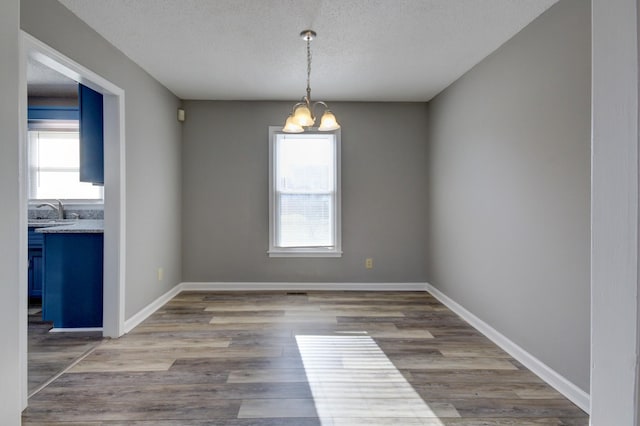 spare room with a notable chandelier, sink, wood-type flooring, and a textured ceiling