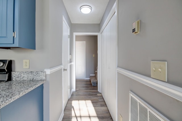 corridor with a textured ceiling and light hardwood / wood-style flooring