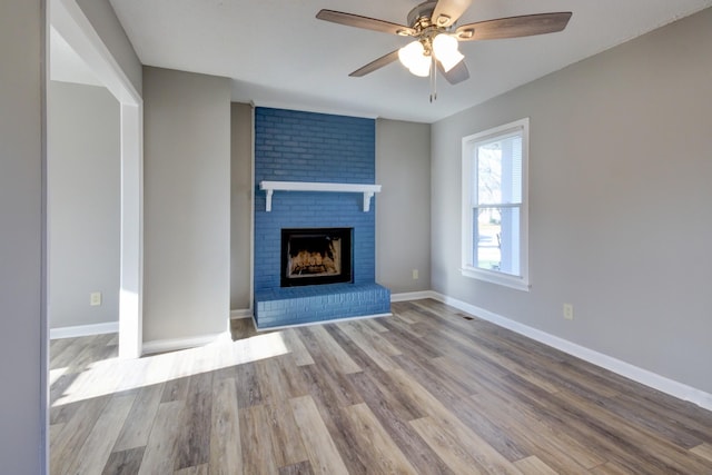 unfurnished living room featuring a brick fireplace, ceiling fan, and light hardwood / wood-style flooring