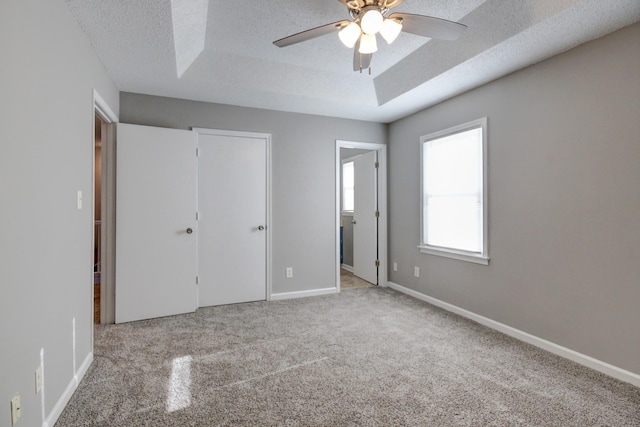 unfurnished bedroom with ceiling fan, light carpet, and a textured ceiling