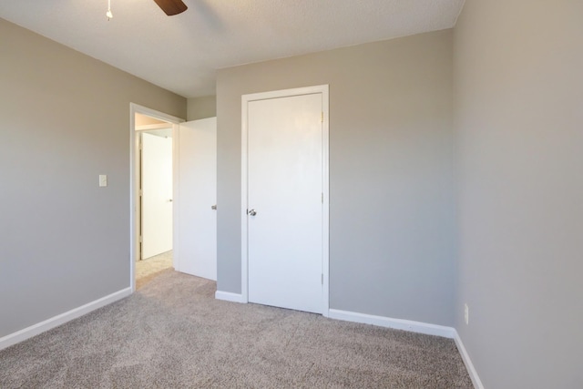 unfurnished bedroom featuring a textured ceiling, ceiling fan, and light carpet