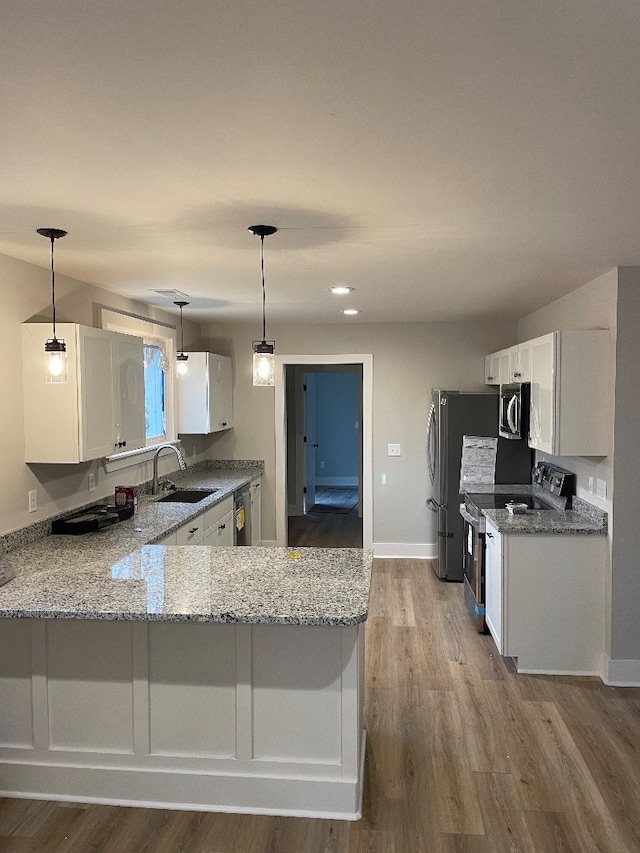 kitchen with kitchen peninsula, sink, white cabinets, and stainless steel appliances