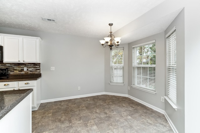 unfurnished dining area with a textured ceiling and a chandelier