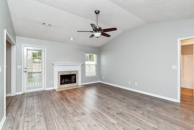 unfurnished living room featuring ceiling fan, a high end fireplace, light hardwood / wood-style floors, and vaulted ceiling