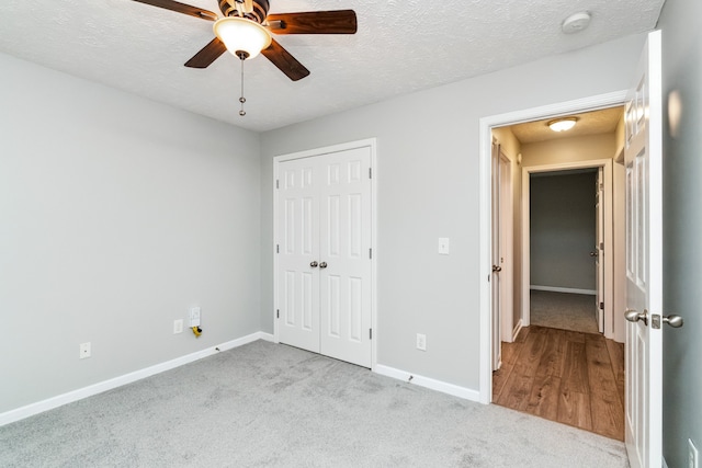 unfurnished bedroom with ceiling fan, light colored carpet, a textured ceiling, and a closet