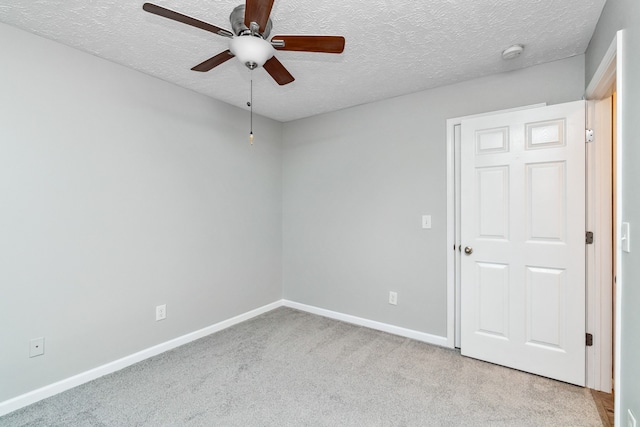 spare room with ceiling fan, light colored carpet, and a textured ceiling