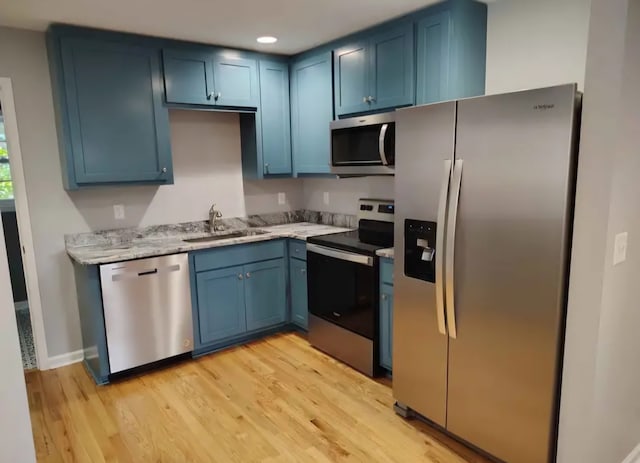 kitchen with blue cabinetry, sink, stainless steel appliances, and light wood-type flooring