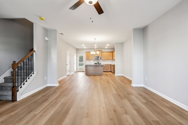 unfurnished living room featuring light hardwood / wood-style flooring and ceiling fan with notable chandelier