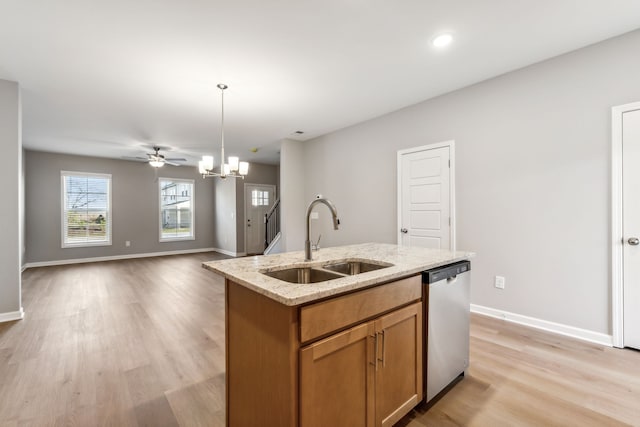 kitchen with dishwasher, a kitchen island with sink, sink, light hardwood / wood-style flooring, and decorative light fixtures