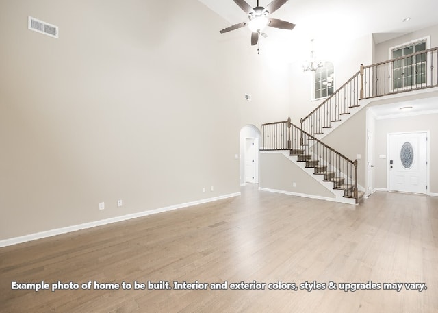 unfurnished living room featuring ceiling fan, light hardwood / wood-style floors, and a towering ceiling