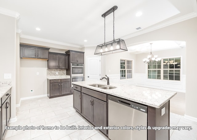 kitchen featuring dark brown cabinetry, stainless steel appliances, sink, pendant lighting, and a center island with sink