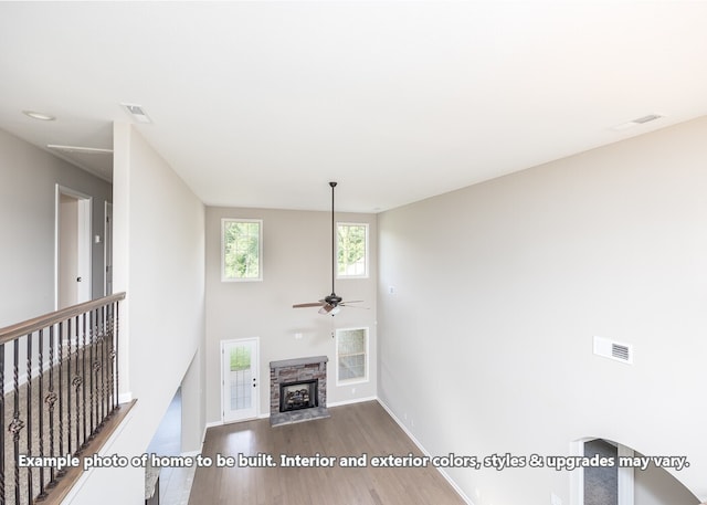 unfurnished living room with ceiling fan, wood-type flooring, and a fireplace