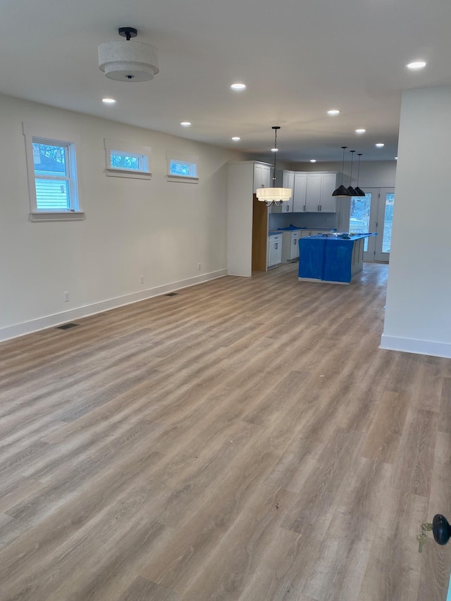 unfurnished living room featuring plenty of natural light and light hardwood / wood-style floors