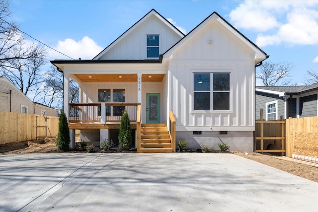 modern farmhouse style home featuring board and batten siding, fence, covered porch, and crawl space