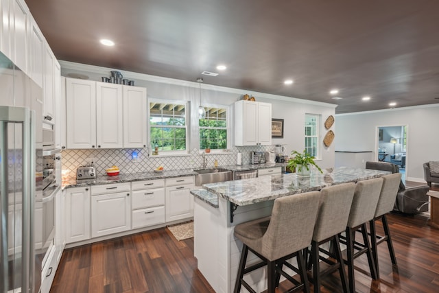 kitchen with a kitchen island, white cabinets, a kitchen breakfast bar, and sink