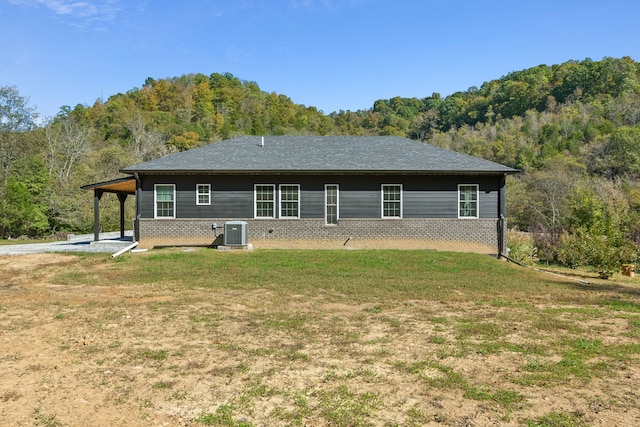 rear view of property featuring central AC unit and a lawn