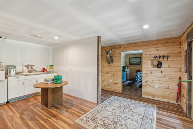 kitchen featuring sink, white cabinetry, wooden walls, and hardwood / wood-style flooring