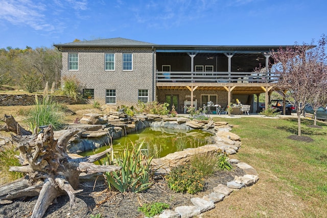 rear view of house with a lawn, a garden pond, a wooden deck, and a patio