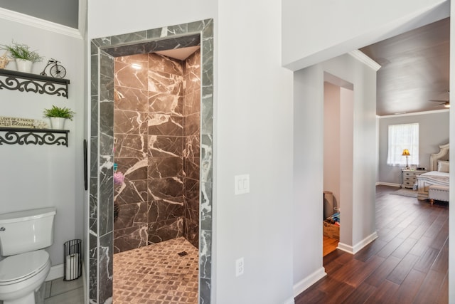 bathroom featuring ceiling fan, toilet, wood-type flooring, tiled shower, and crown molding