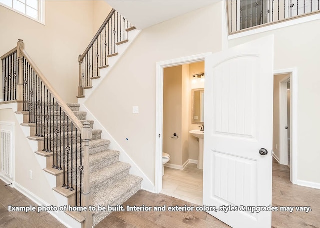 stairway with baseboards, a high ceiling, and wood finished floors