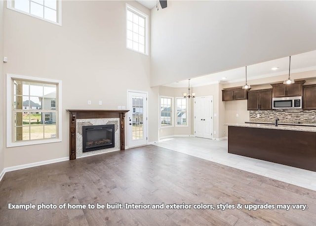 unfurnished living room with baseboards, a glass covered fireplace, light wood-style flooring, and a healthy amount of sunlight