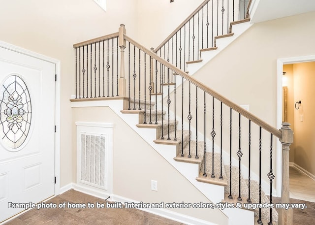 stairs featuring visible vents, a towering ceiling, and baseboards