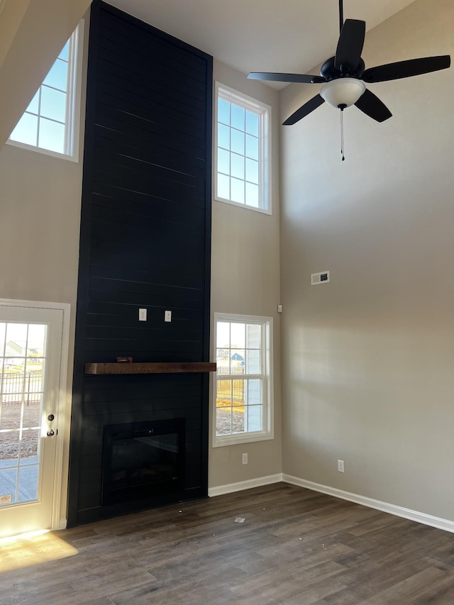 unfurnished living room featuring a healthy amount of sunlight, visible vents, a fireplace, and wood finished floors