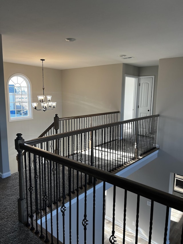 stairway with a notable chandelier