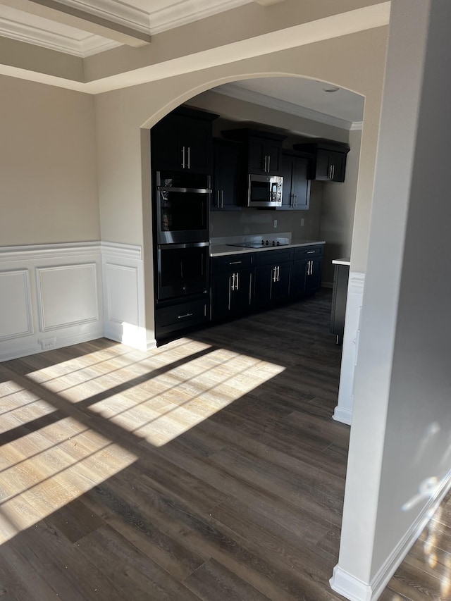 bar featuring wainscoting, stainless steel microwave, dark wood-type flooring, black electric cooktop, and crown molding