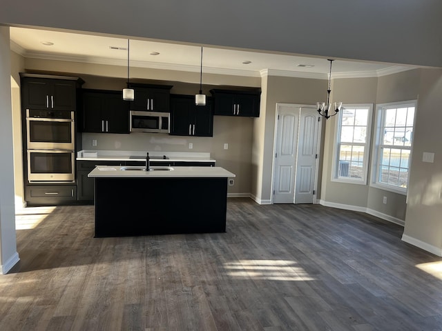 kitchen featuring stainless steel appliances, light countertops, dark cabinetry, and a sink