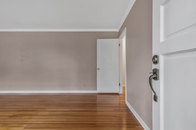 empty room with hardwood / wood-style floors and crown molding