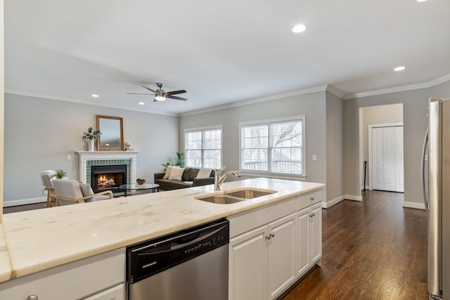 kitchen featuring dark hardwood / wood-style flooring, a brick fireplace, stainless steel appliances, sink, and white cabinetry