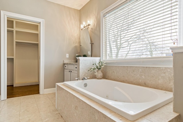 bathroom featuring tile patterned flooring, vanity, and a relaxing tiled tub