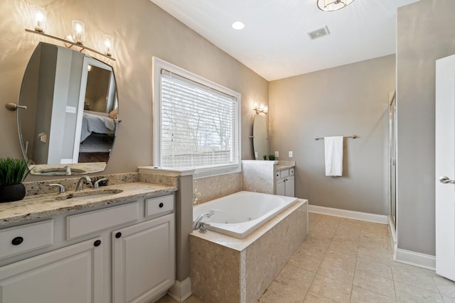 bathroom featuring tile patterned flooring, vanity, and tiled tub