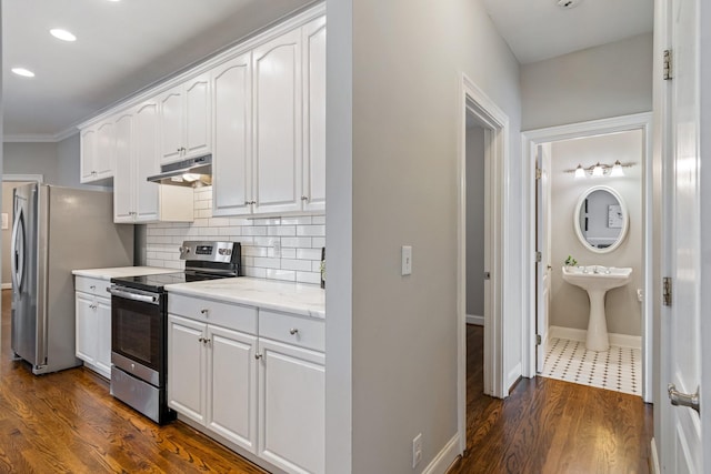 kitchen with dark hardwood / wood-style flooring, stainless steel appliances, white cabinetry, and ornamental molding