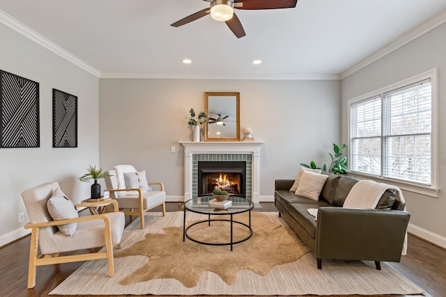 living room featuring a fireplace, light hardwood / wood-style floors, ceiling fan, and crown molding