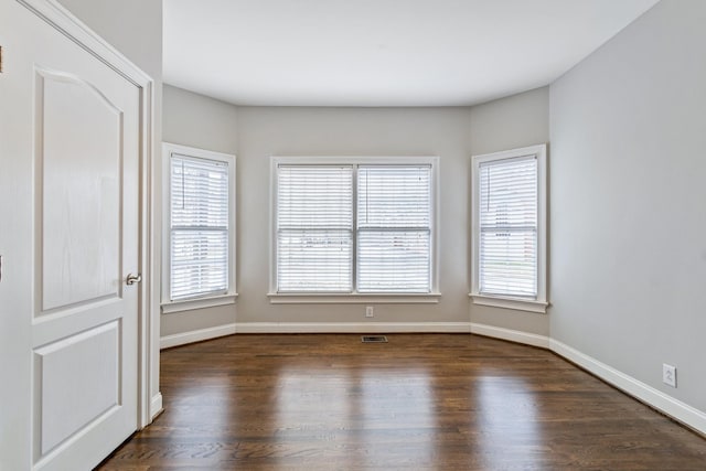 empty room featuring plenty of natural light and dark hardwood / wood-style floors