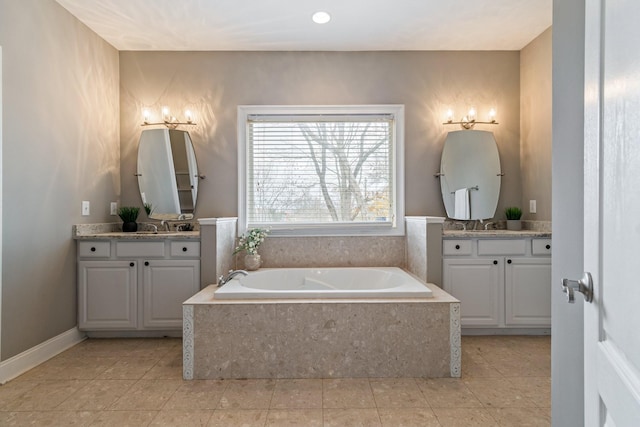 bathroom with tile patterned flooring, vanity, and tiled tub